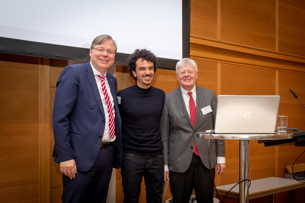 Prof. Spitzer und Prof. Holzgreve vom Vorstand der DGIV verleihen den mit 1.000 Euro dotierten Preis an Amyn Vogel, MSc.